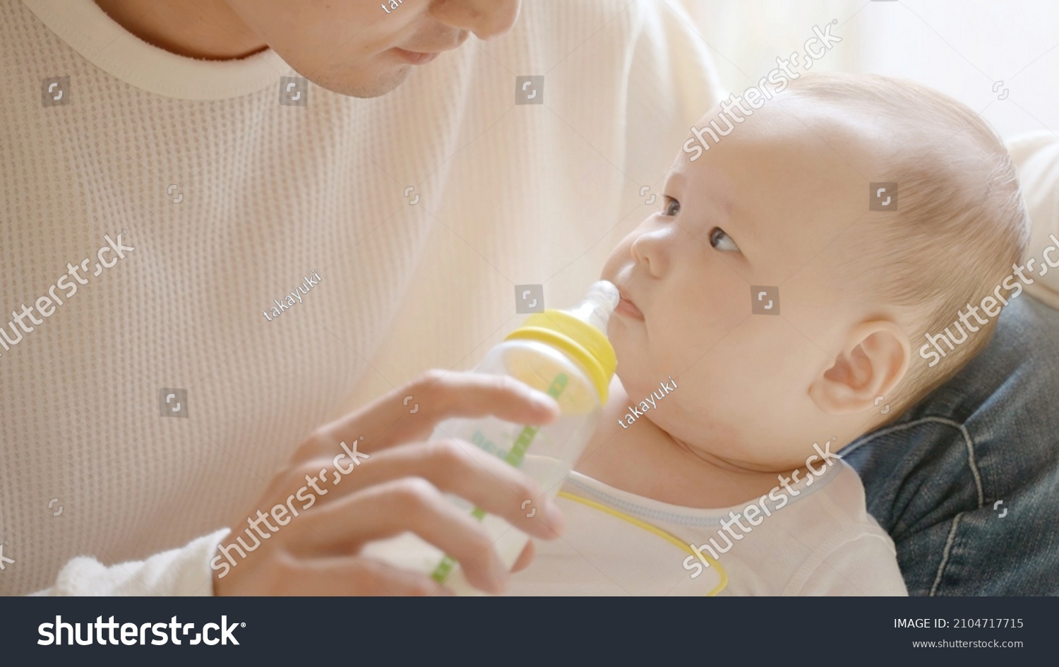 portrait of young father giving milk to baby boy