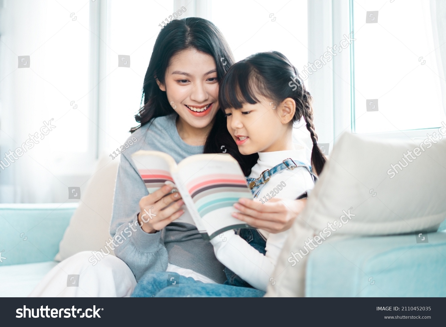 image of mother and daughter sitting on the sofa reading a book