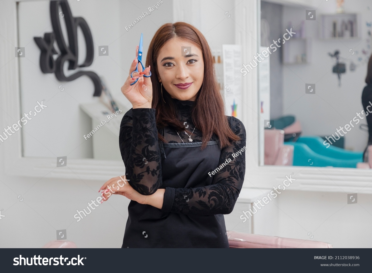 Hispanic hairstylist in her beauty salon posing with her scissors. enterprising professional woman in her business - proud professional hairdresser