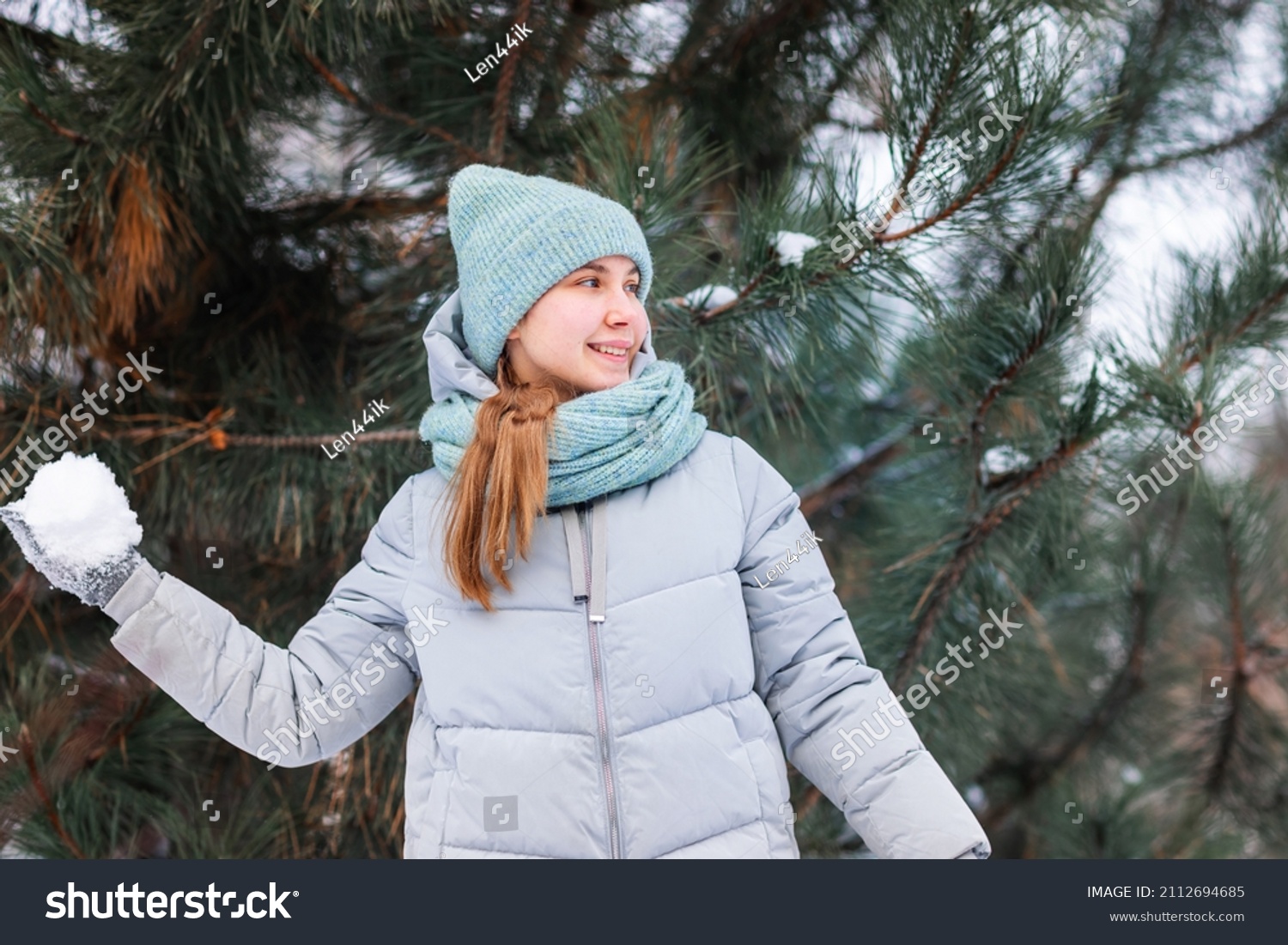Happy teenage girl having fun playing with snowballs  ready to throw the snowball. Snow games. Winter vacation.