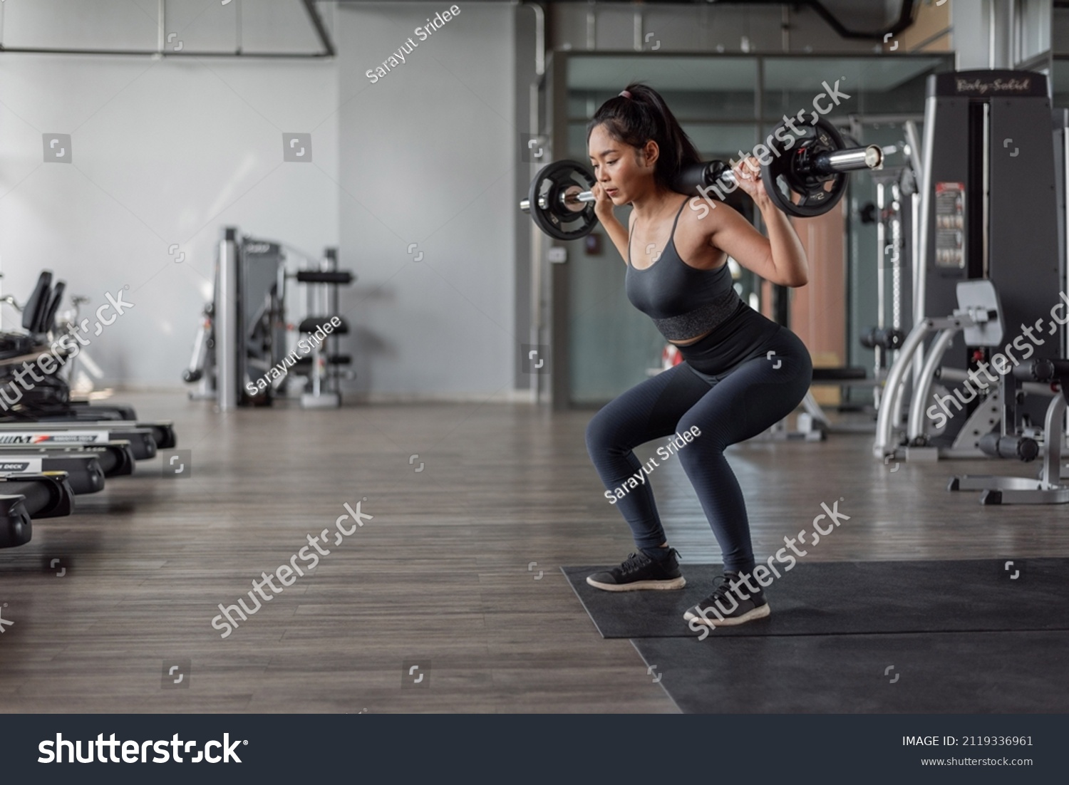 Asian woman exercise in fitness. Young healthy woman in sportswear doing legs exercise in fitness.
