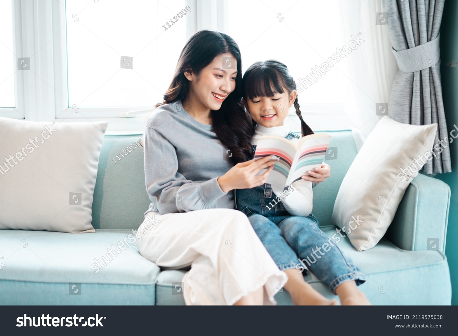 image of mother and daughter sitting on the sofa reading a book