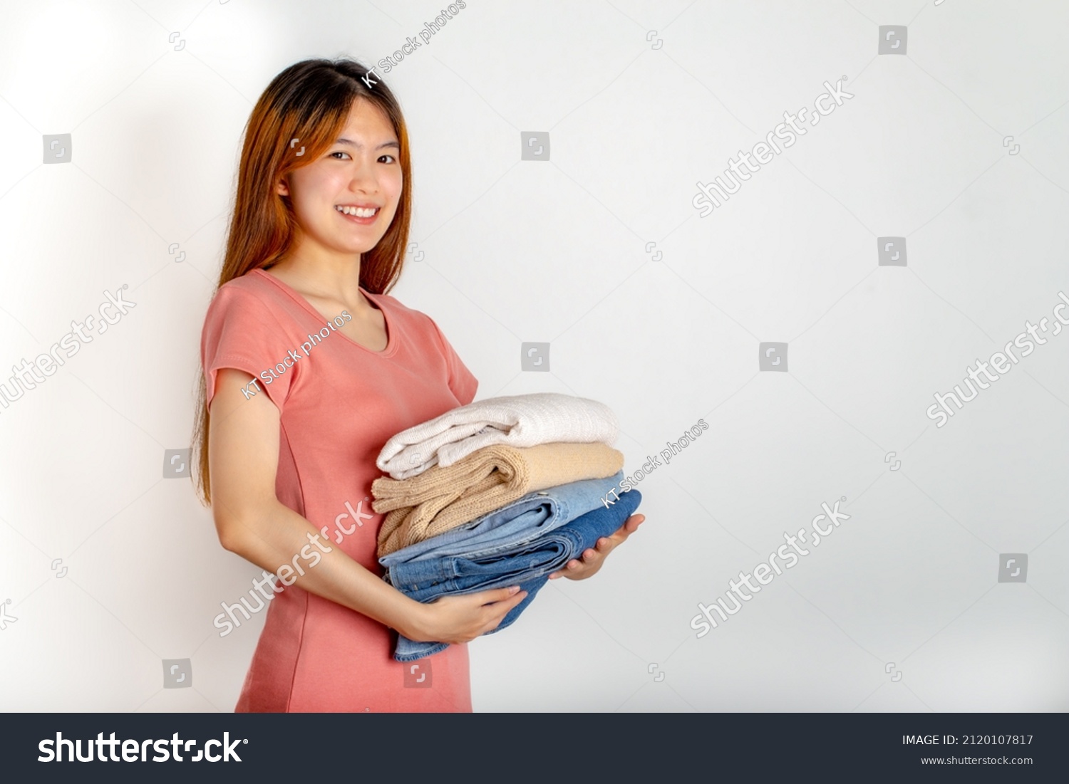 Asian woman smile and holding folded clothes in hands.