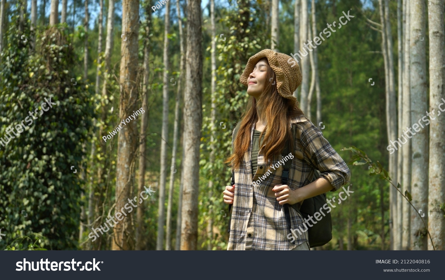 Happy young asian woman with backpack in the forest smiling and feeling the nature enjoy traveling on holidays.