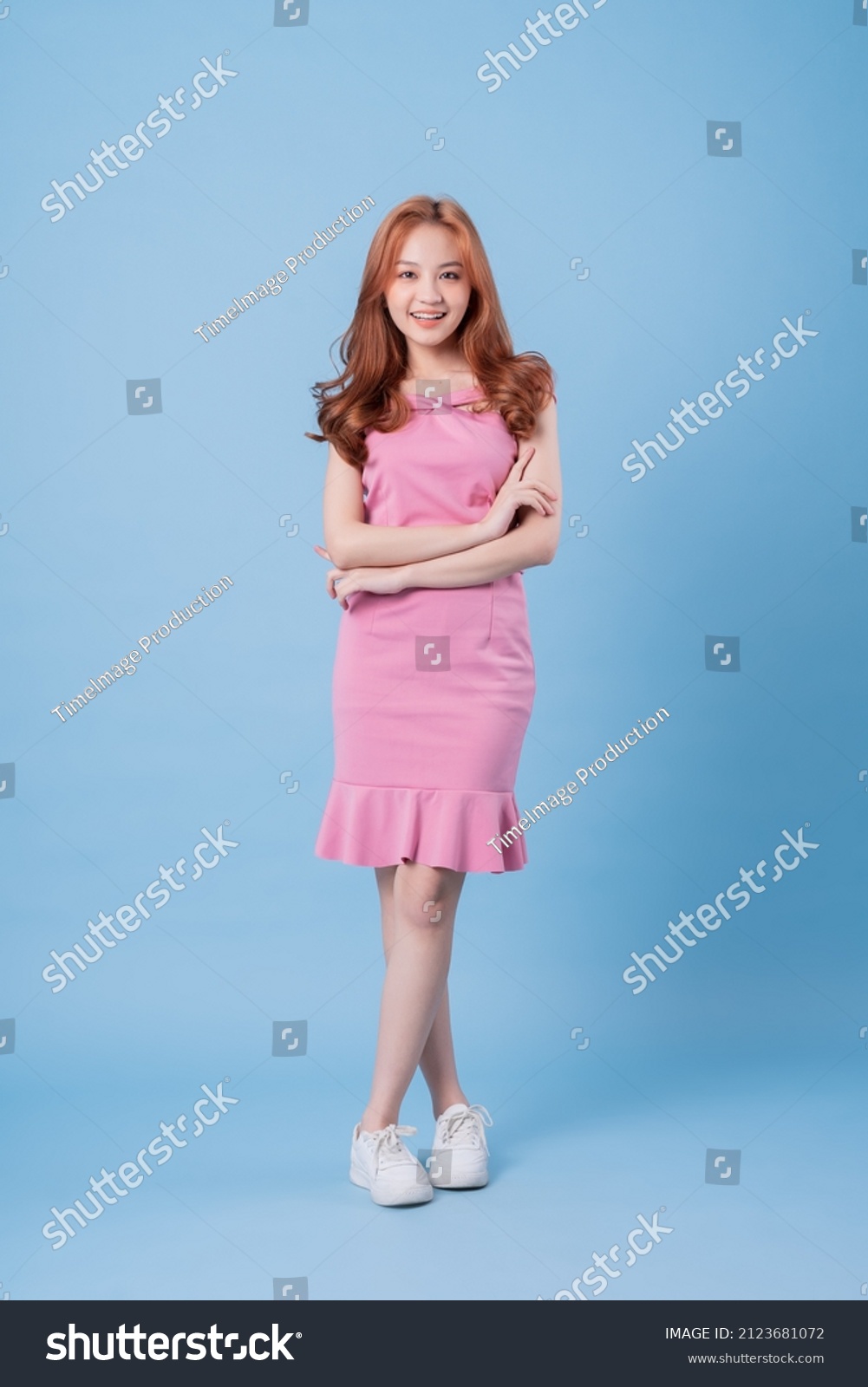 Young Asian woman wearing pink dress and posing on blue background