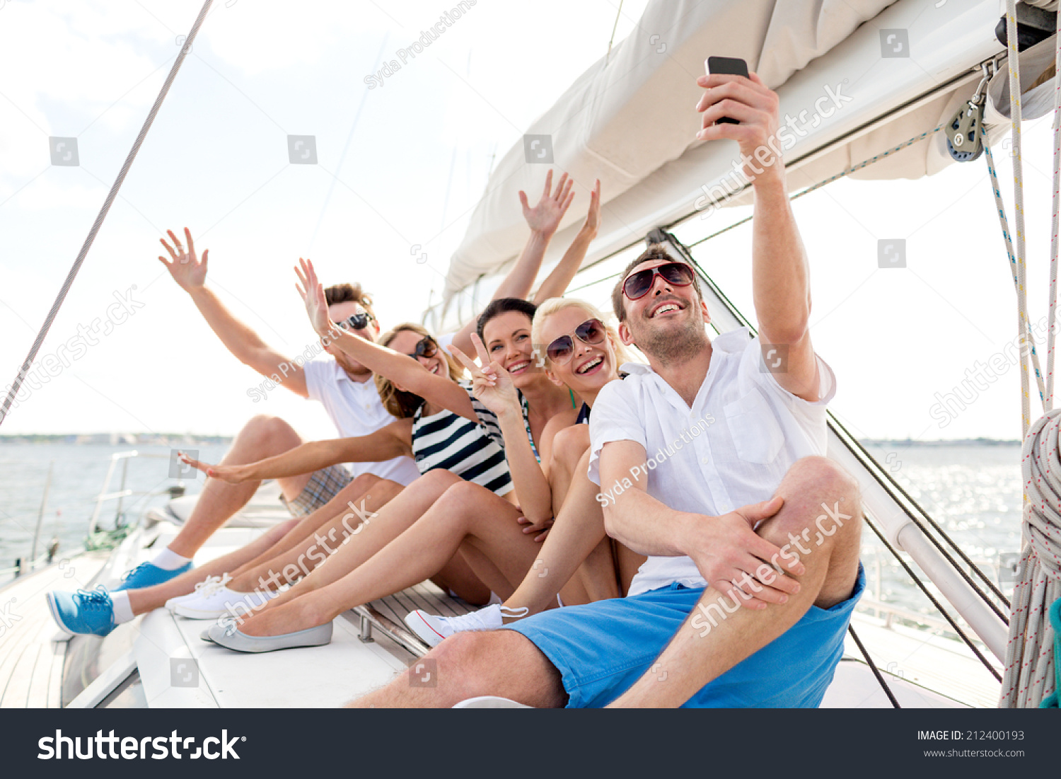 vacation travel sea friendship and people concept - smiling friends sitting on yacht deck and making selfie