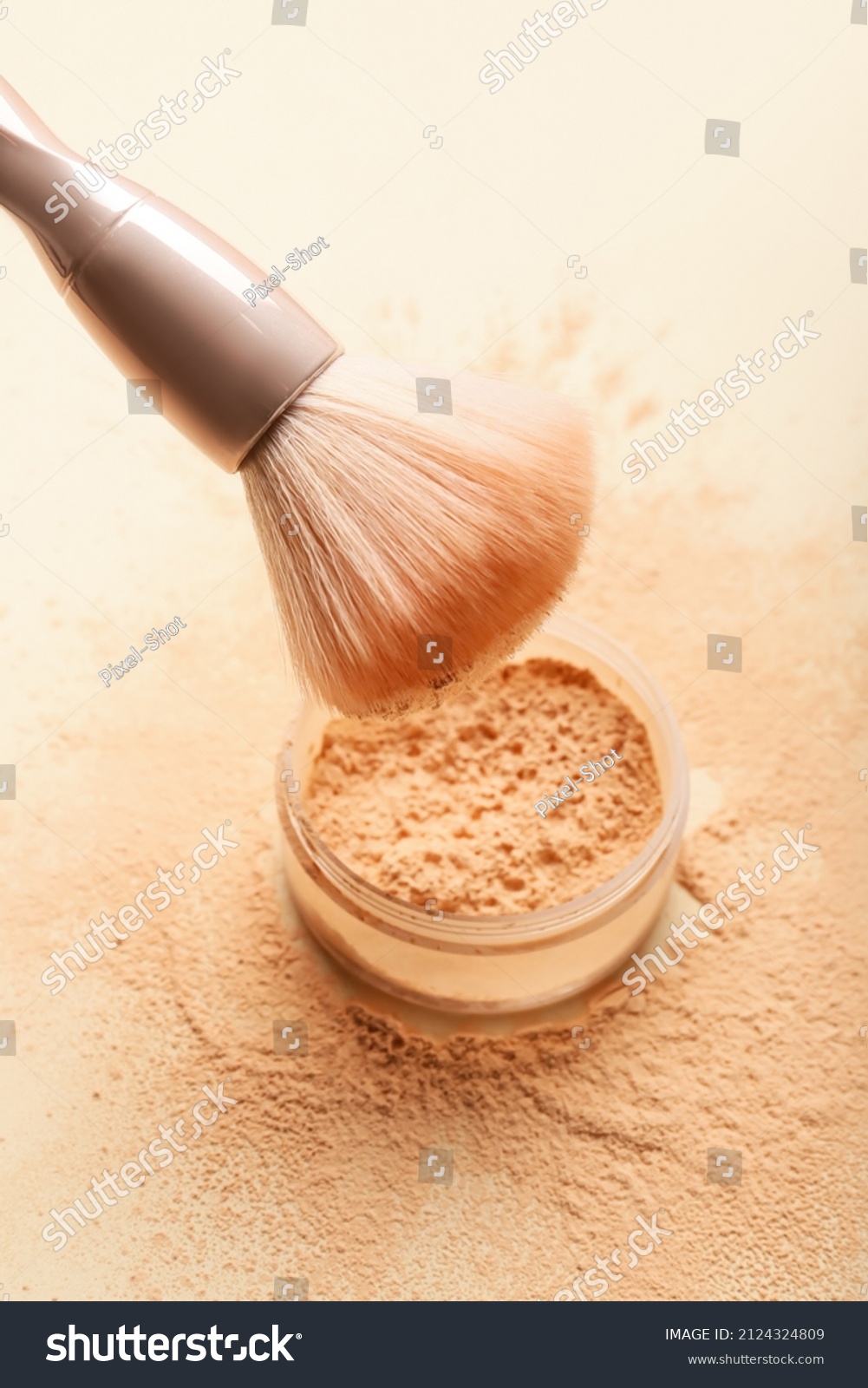 Makeup brush and loose powder on light background