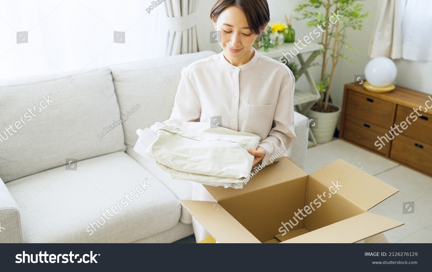 Asian woman putting clothes away in a box
