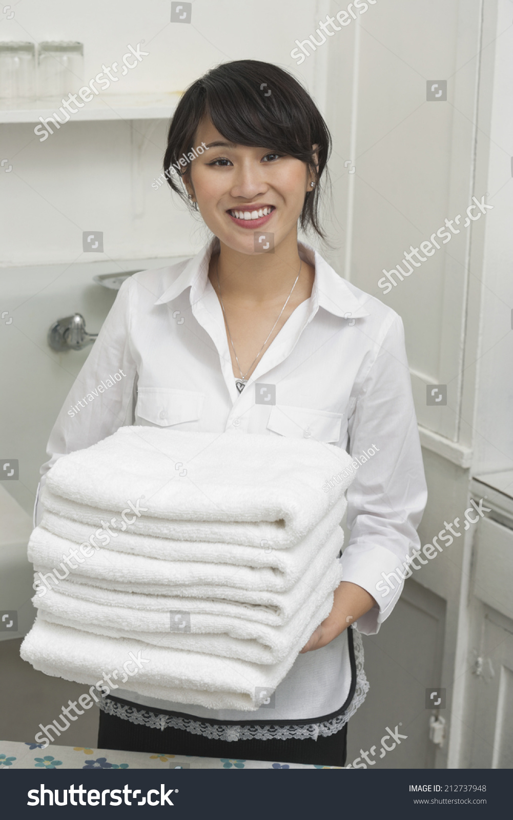 Portrait of young female housekeeper holding clean white folded towels