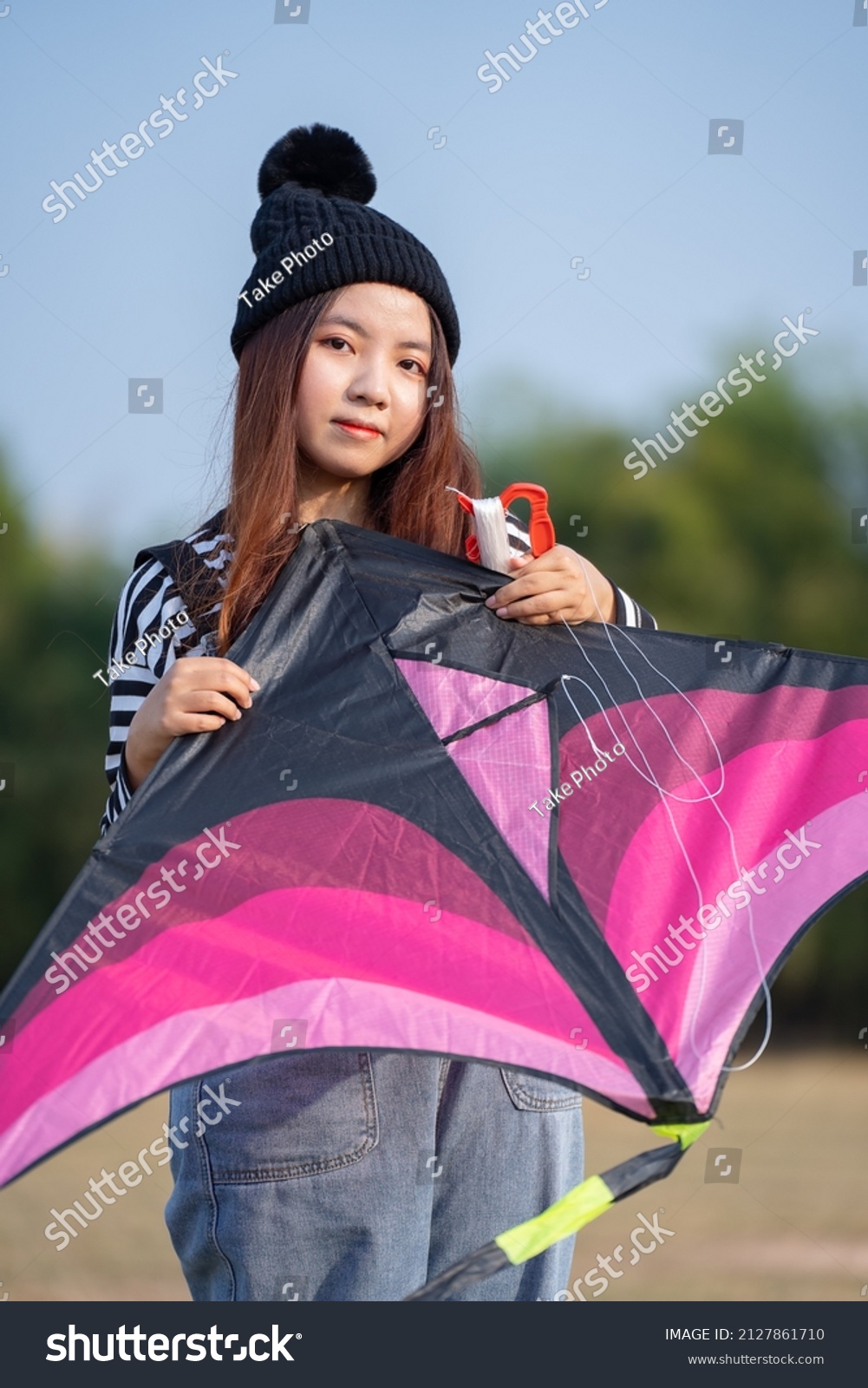 Young woman playing kite at the grass field. asian girl flying a kite in summer