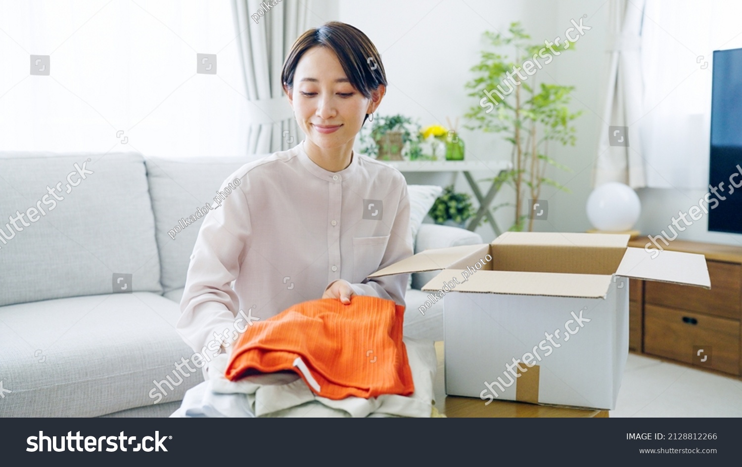 Asian woman putting clothes away in a box
