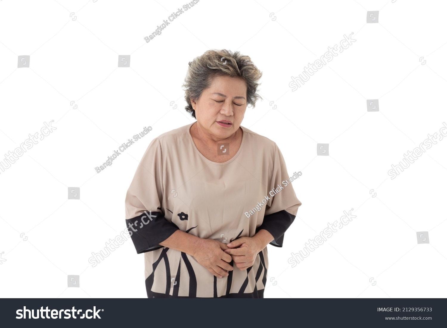 Isolated cutout studio shot Asian old senior sick retired gray short hair grandmother model in casual outfit standing holding hands on his tummy  stomachache on white background.