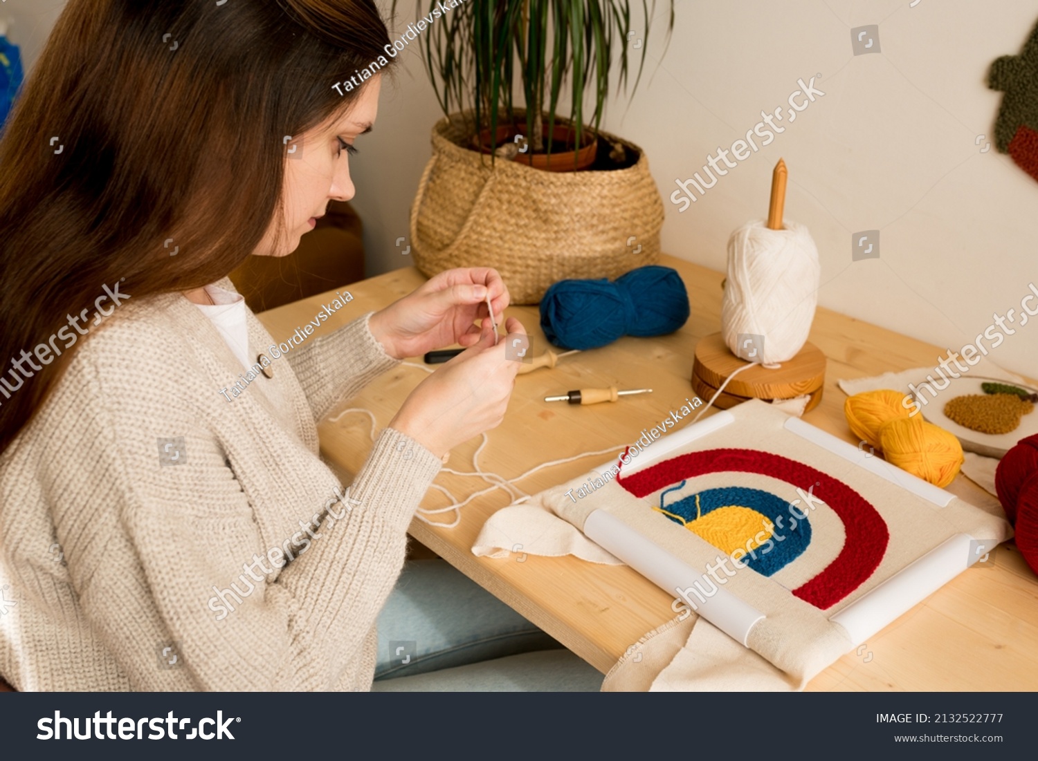 Punch needle embroidery.  Woman making  pillow with creative technique involving the punching and looping of  thread in particular design through ground cloth.