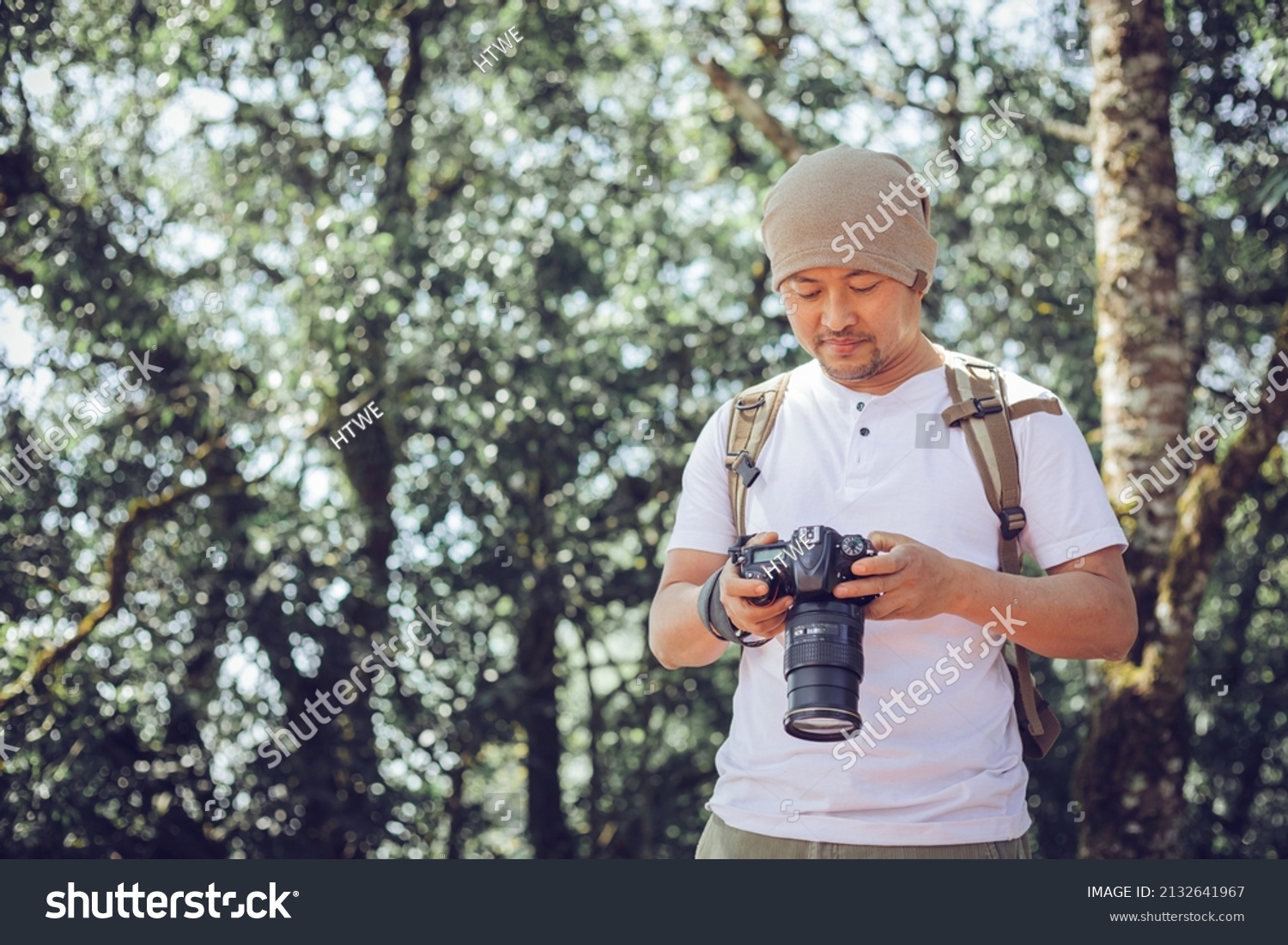 Young male professional photographer holding camera outdoors at the park