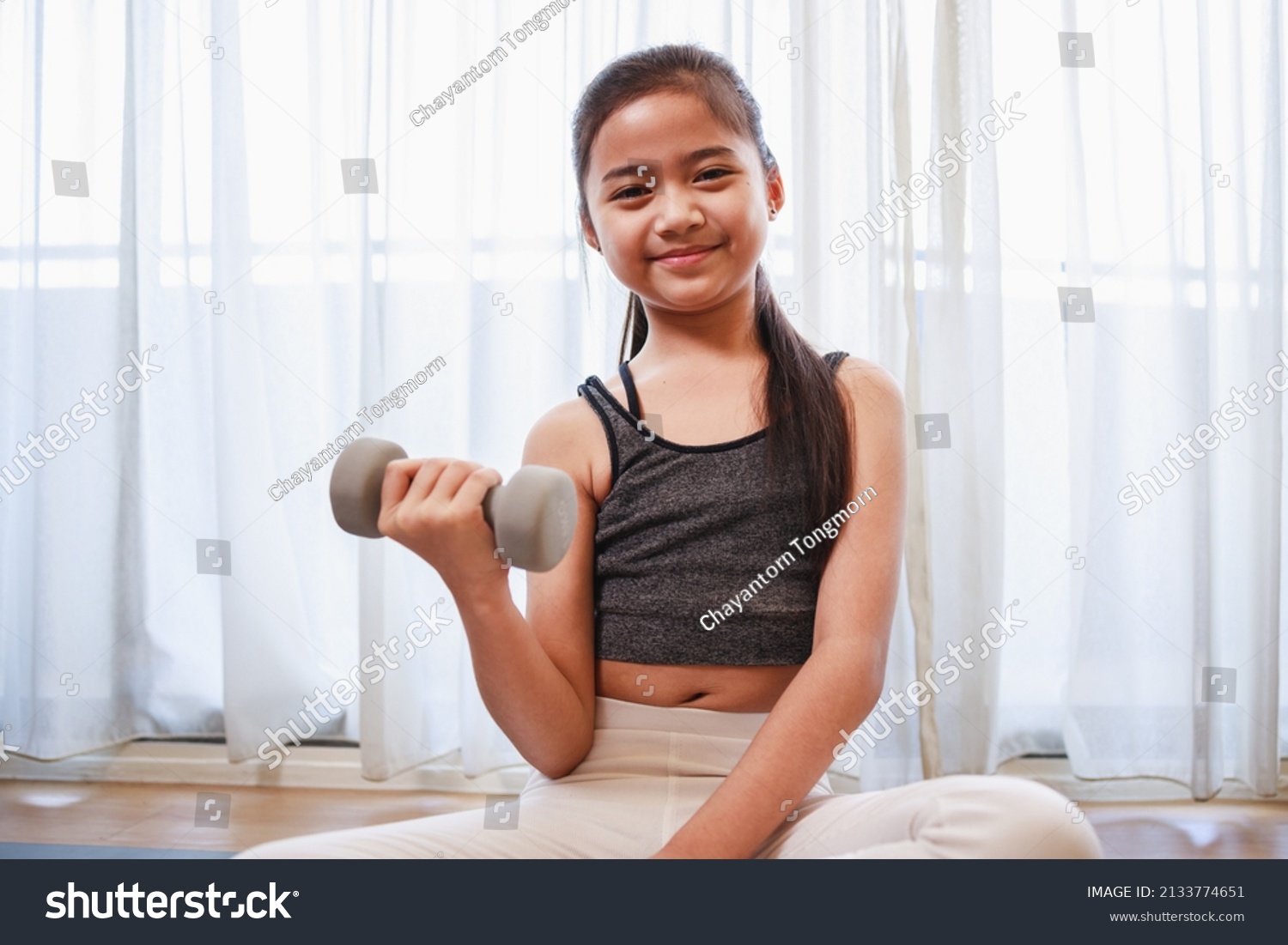 Little Girl doing exercise at home on a yoga mat in the living room at home. New normal concept. Healthy lifestyle. Relaxing at home