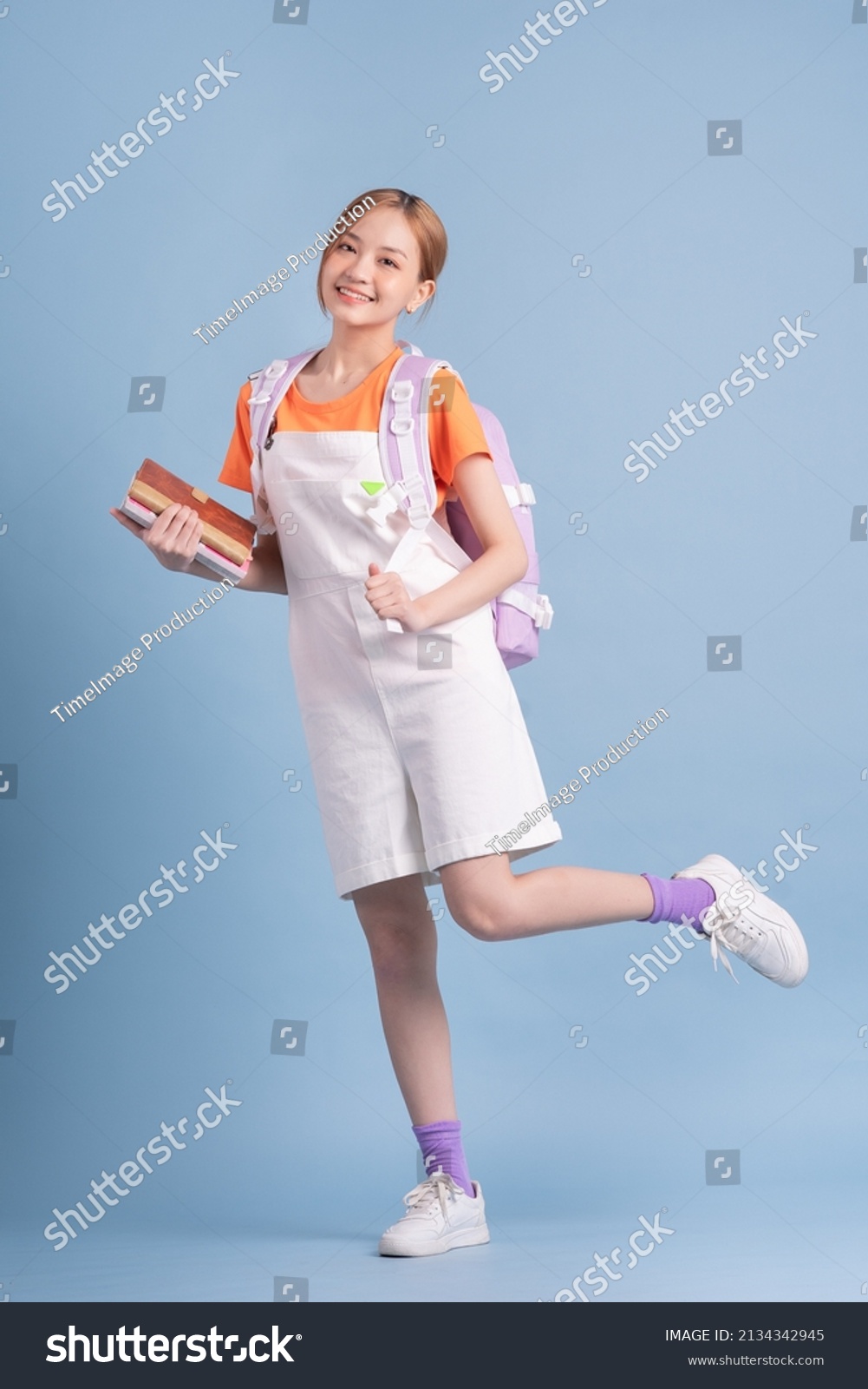 Young Asian student posing on blue background
