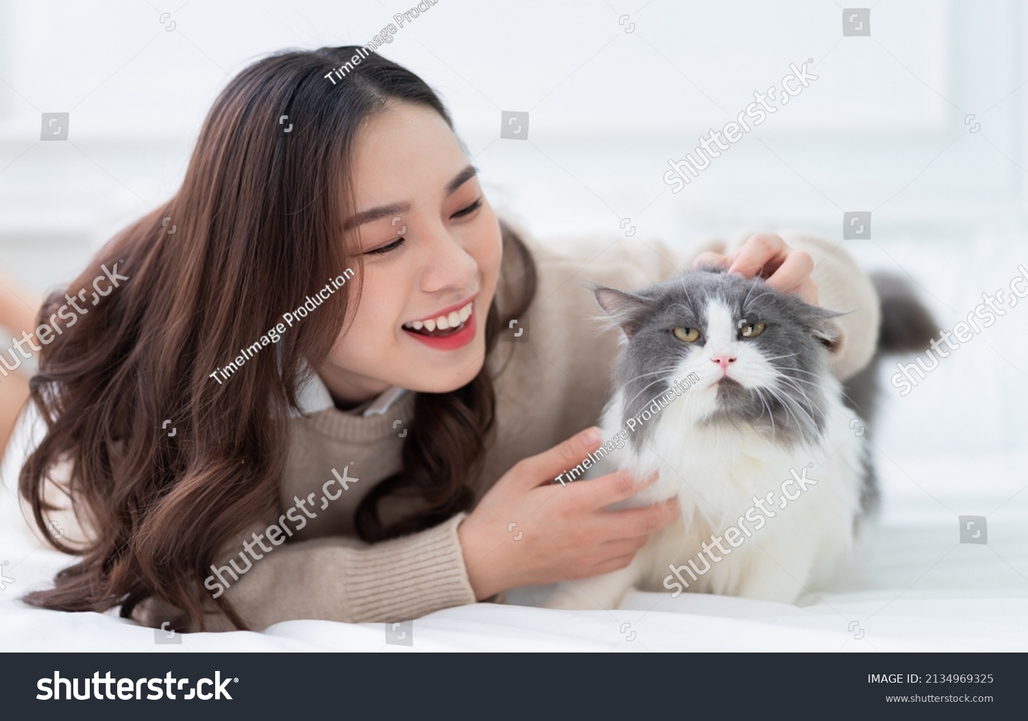 Young Asian woman playing with cat at home