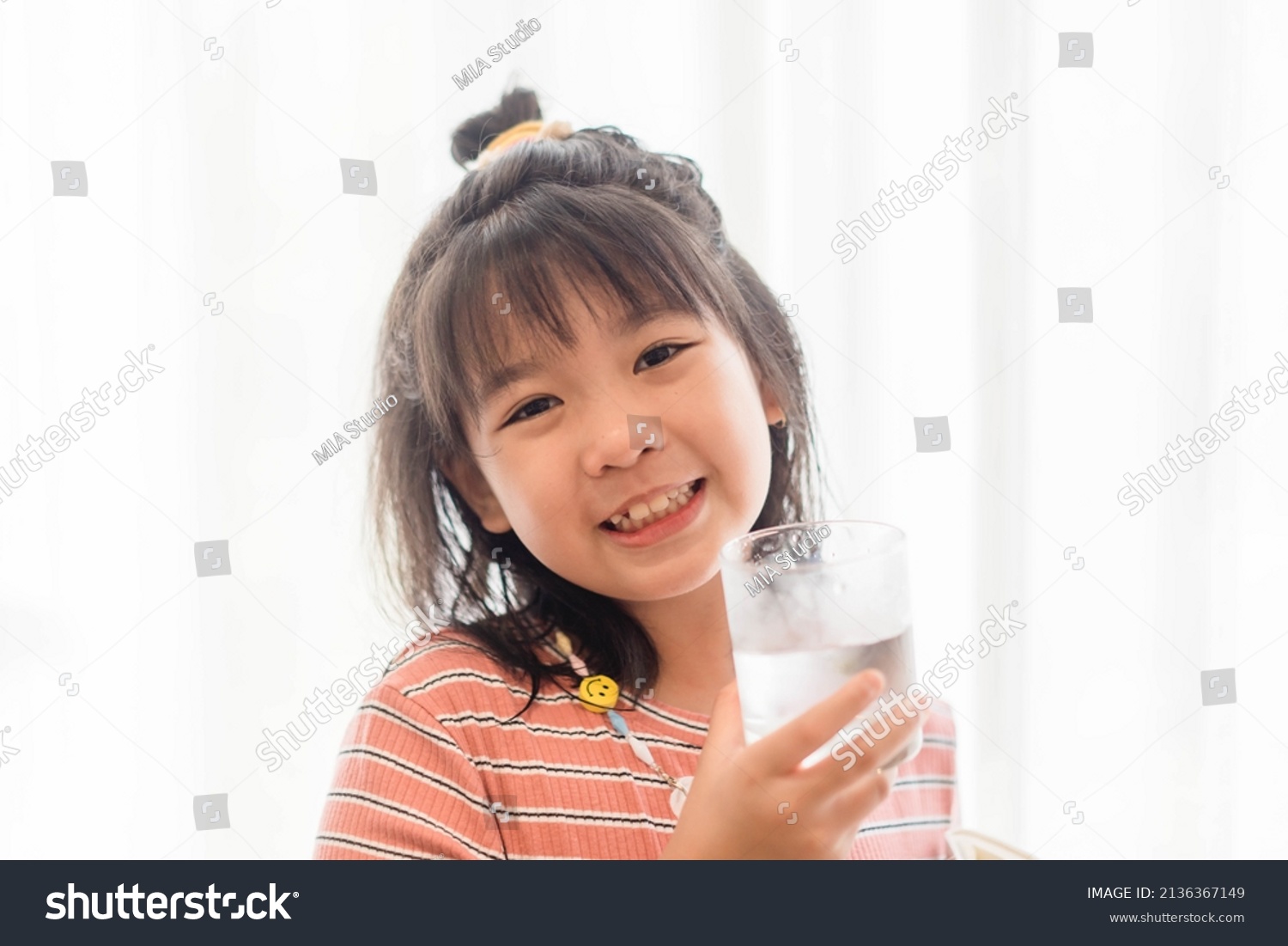 Water drink.Kid girl smile and drinking water from glass isolate white banner background.World water day  Mineral water  fresh drinking  thirsty summer  wellness  healthcare.Young Asian child thirst.