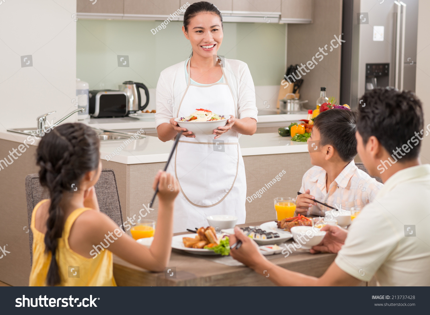 Vietnamese woman bringing dish to dinner table