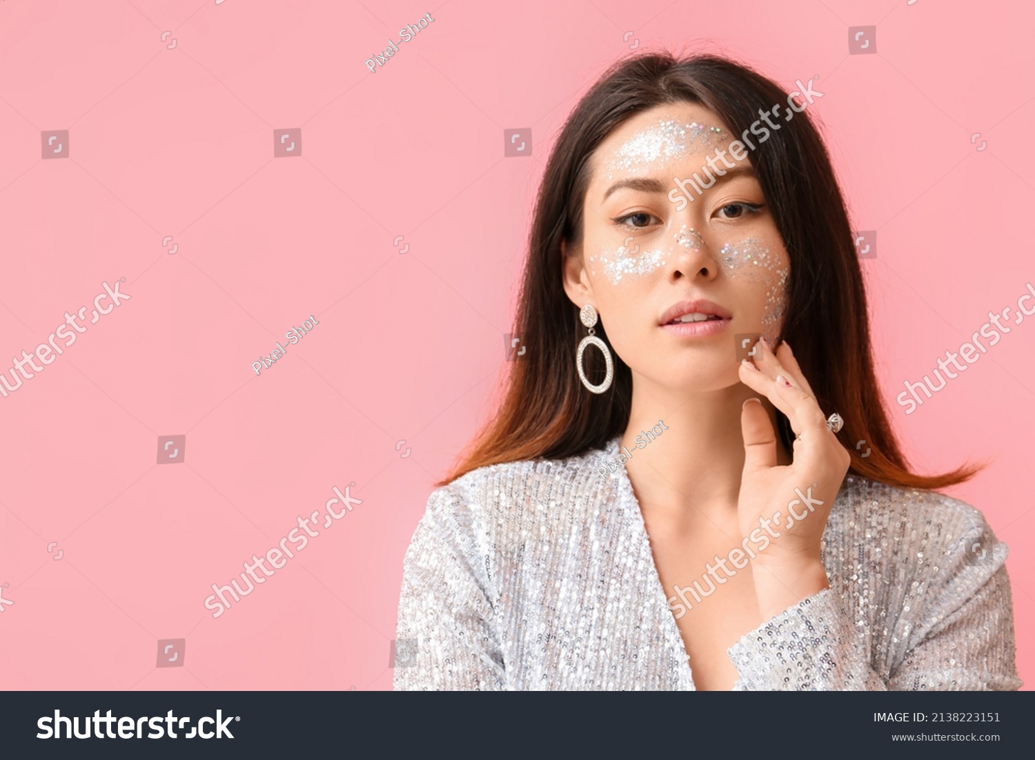 Portrait of fashionable Asian woman with glitter makeup on color background