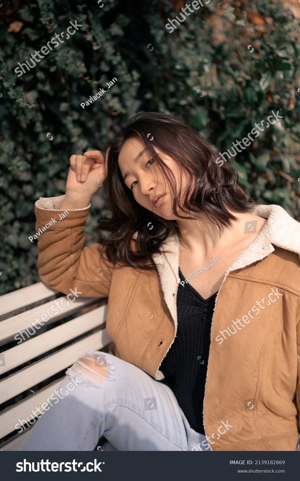 Young Asian woman on bench at city park.