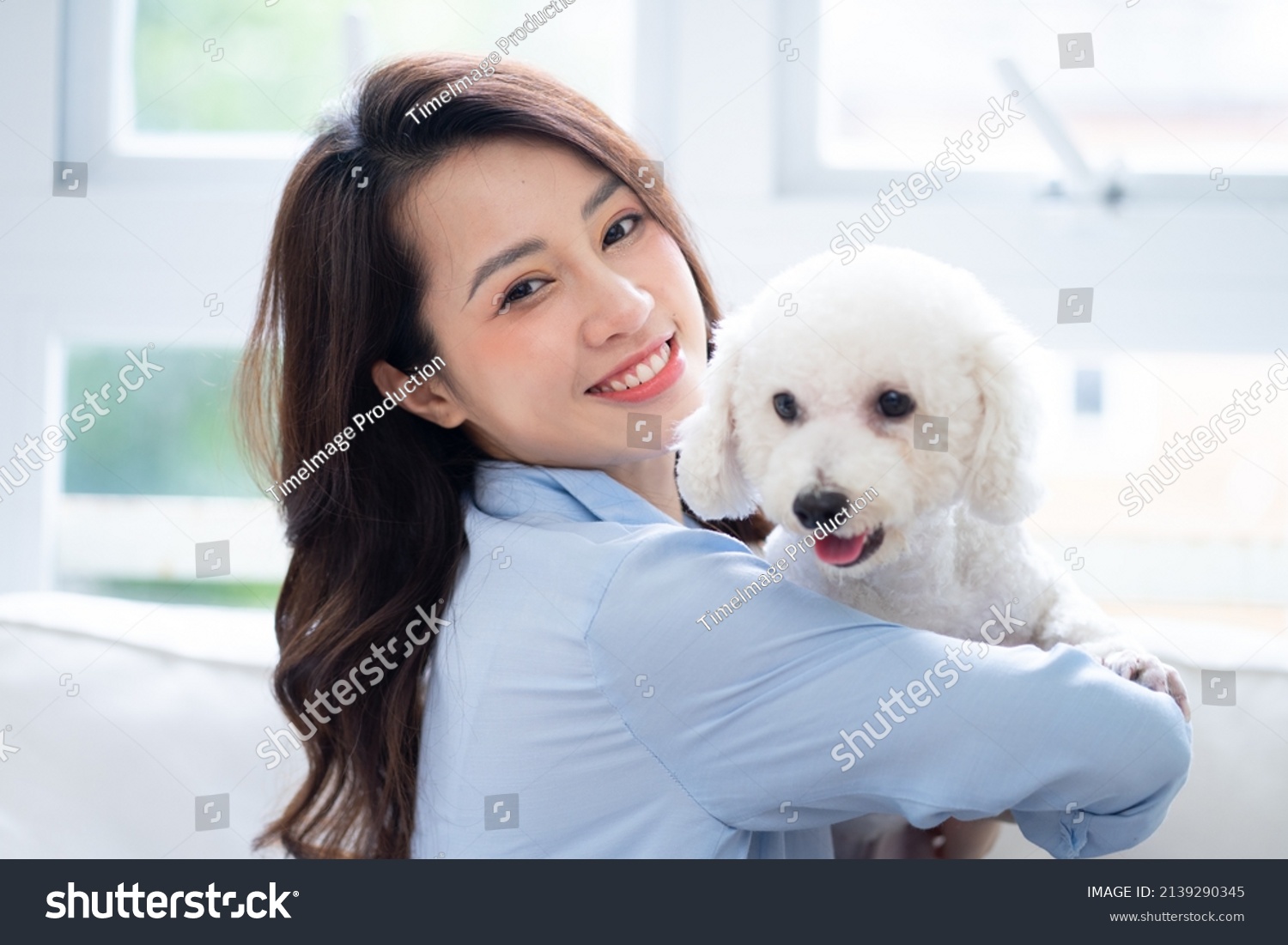 Young Asian woman playing with dog at home