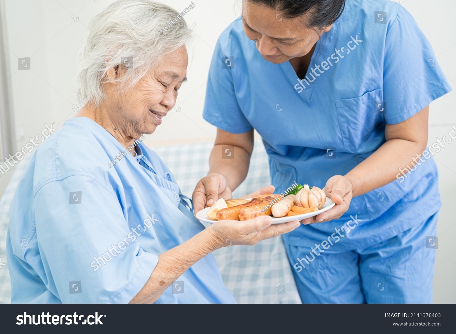 Asian senior or elderly old lady woman patient eating breakfast and vegetable healthy food with hope and happy while sitting and hungry on bed in hospital.