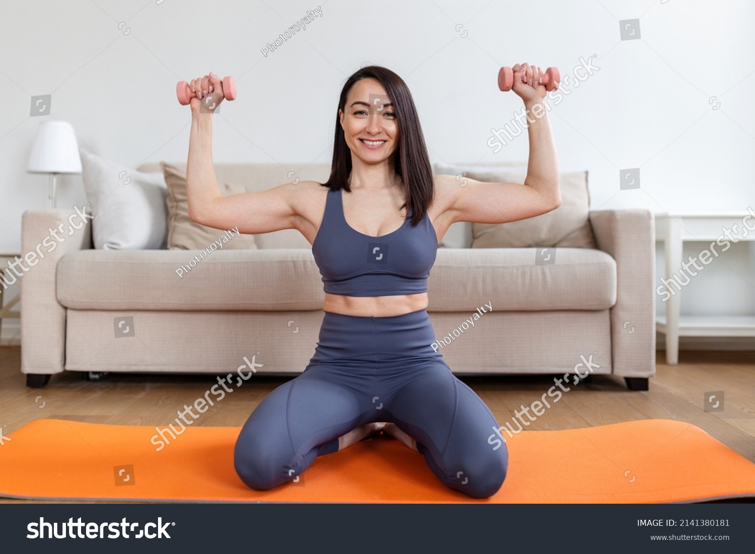 Asian woman exercise with dumbbells at home. Happy female doing arm workout using dumbbells