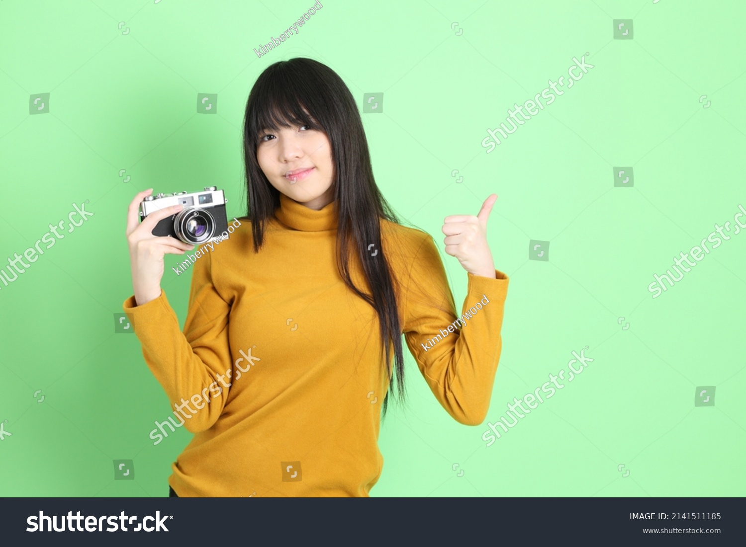 The cute young Asian girl with casual dressed standing on the green background