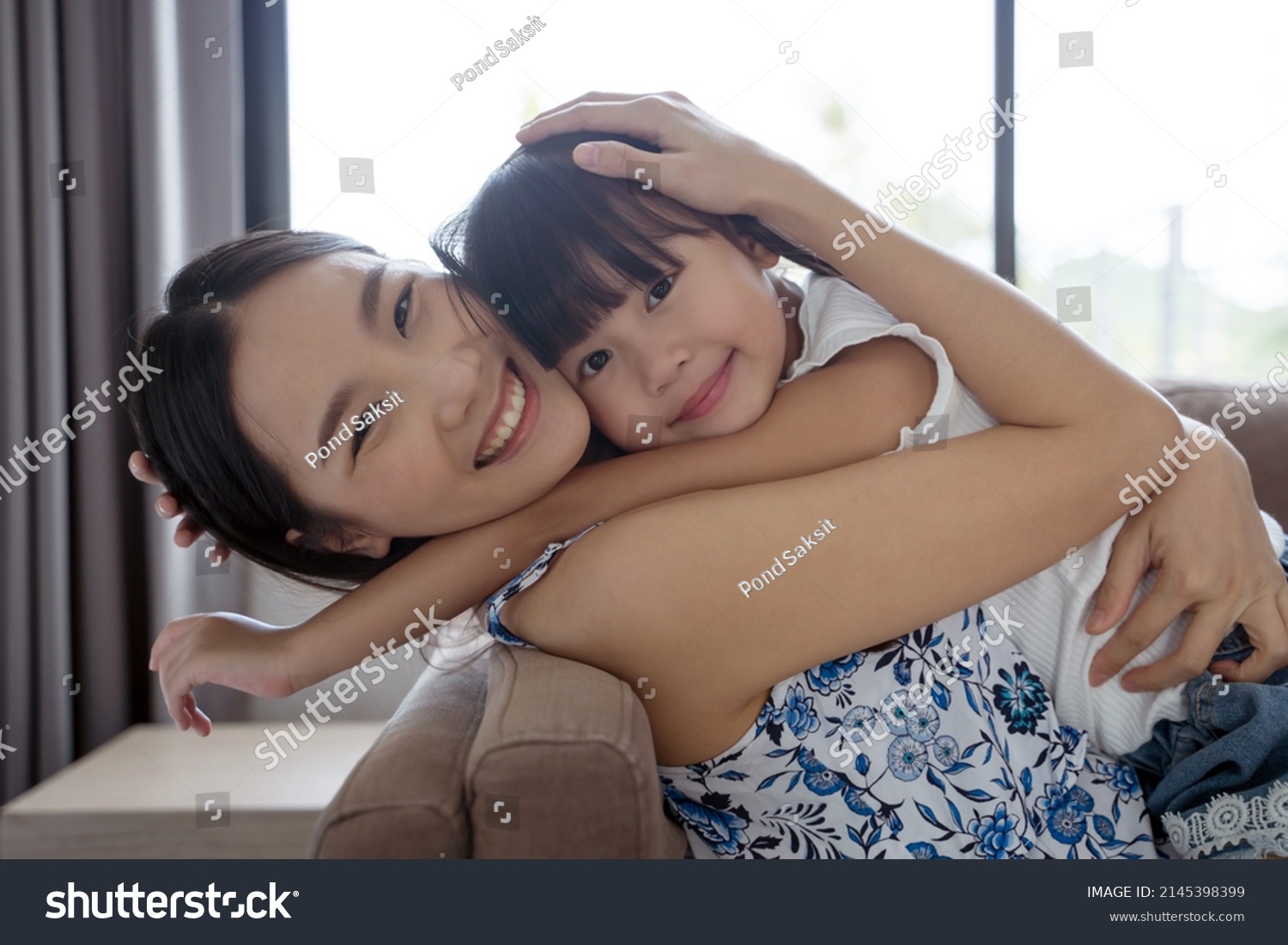 Asian mother and daughter smile and look at camera. Happy love family concept