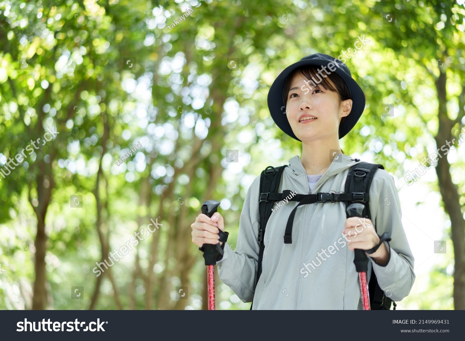 young asian woman using hiking staff walking in a forest