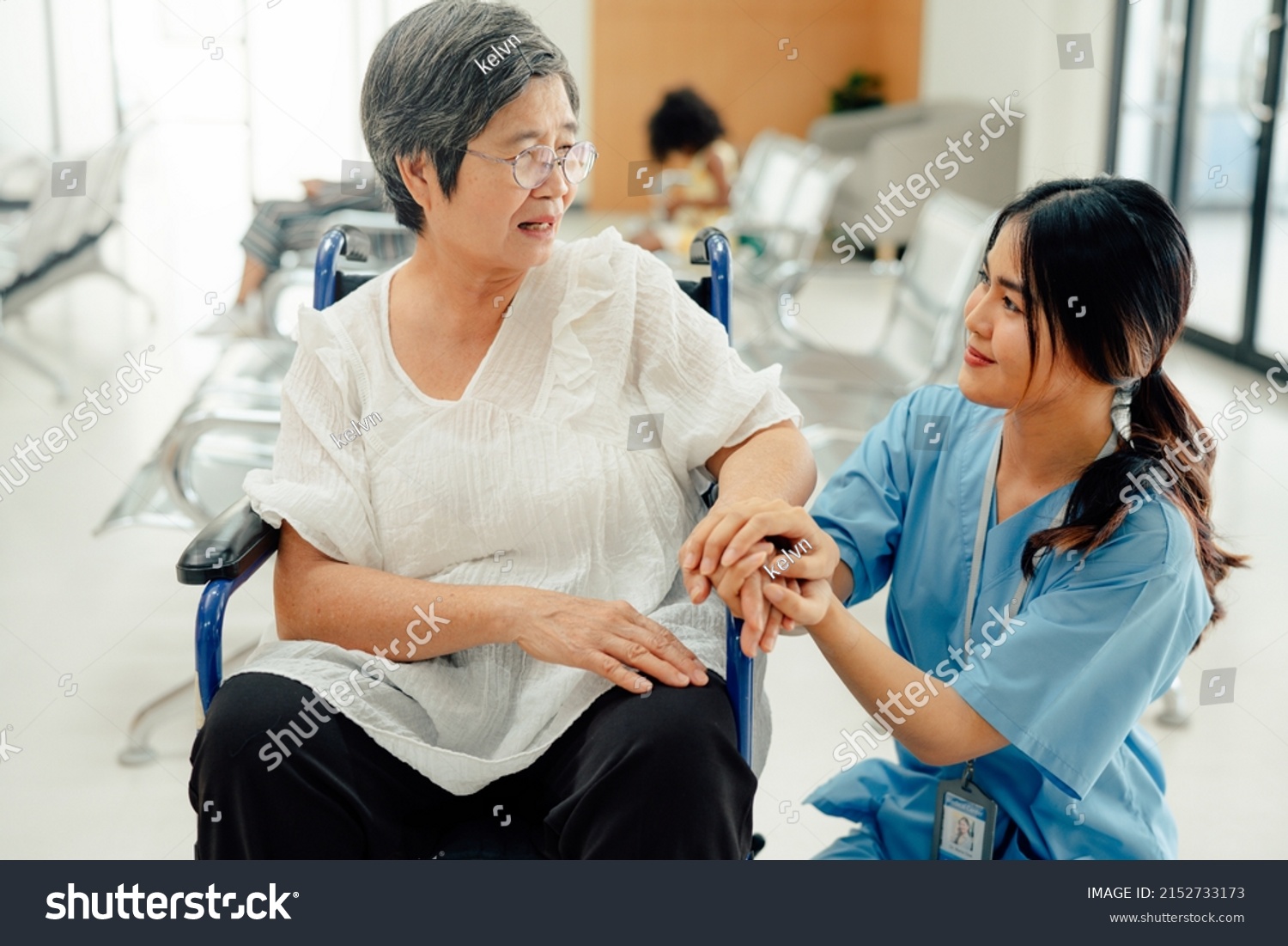 Asian nurse taking care and talking mature female patient sitting on wheelchair in hospital. Healthcare concept.
