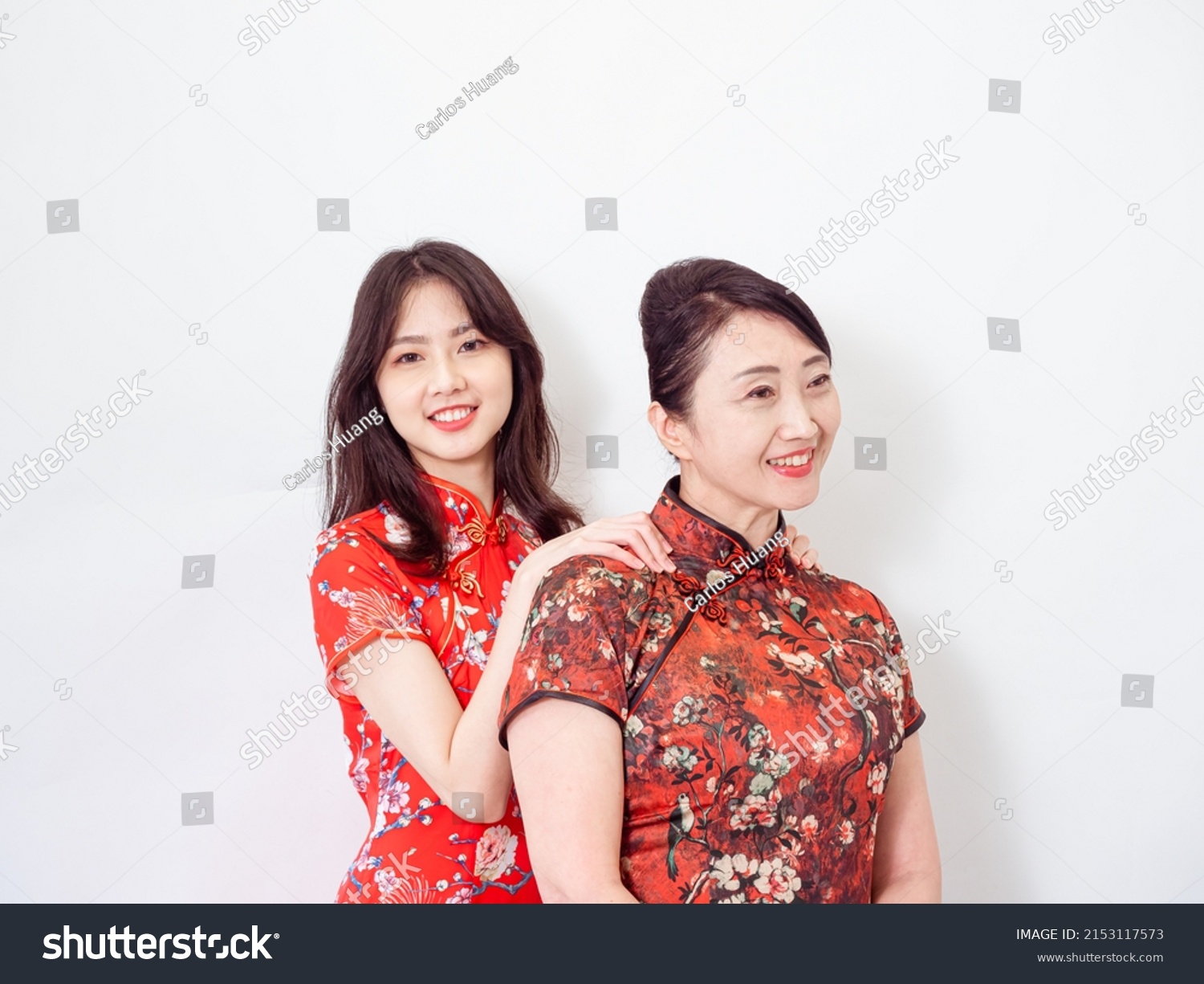 Portrait of Asian Young daughter giving her mother a massage for Relieve stress on white background(both wearing traditional cheongsam qipao dress).