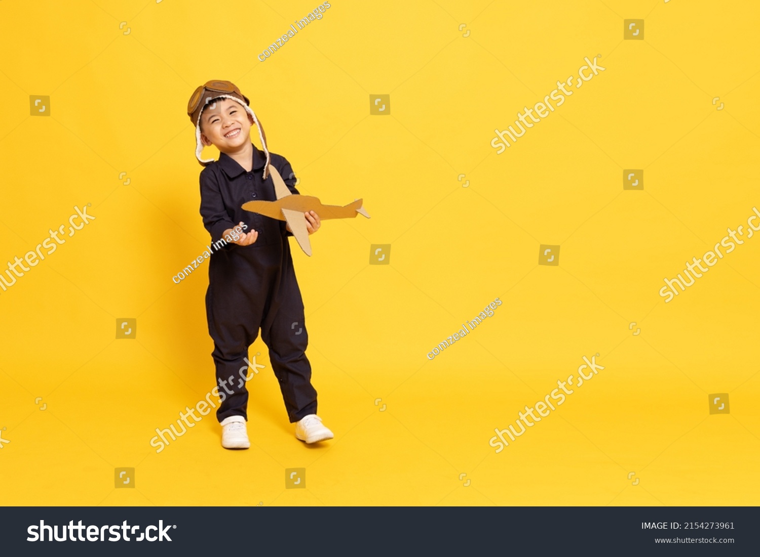 Asian little boy playing with cardboard airplane isolated on yellow background