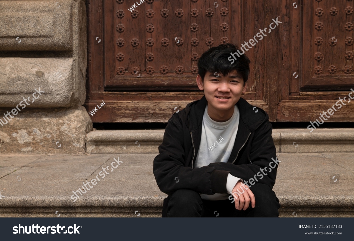 Portrait of teenage Asian boy sitting on stairway against building