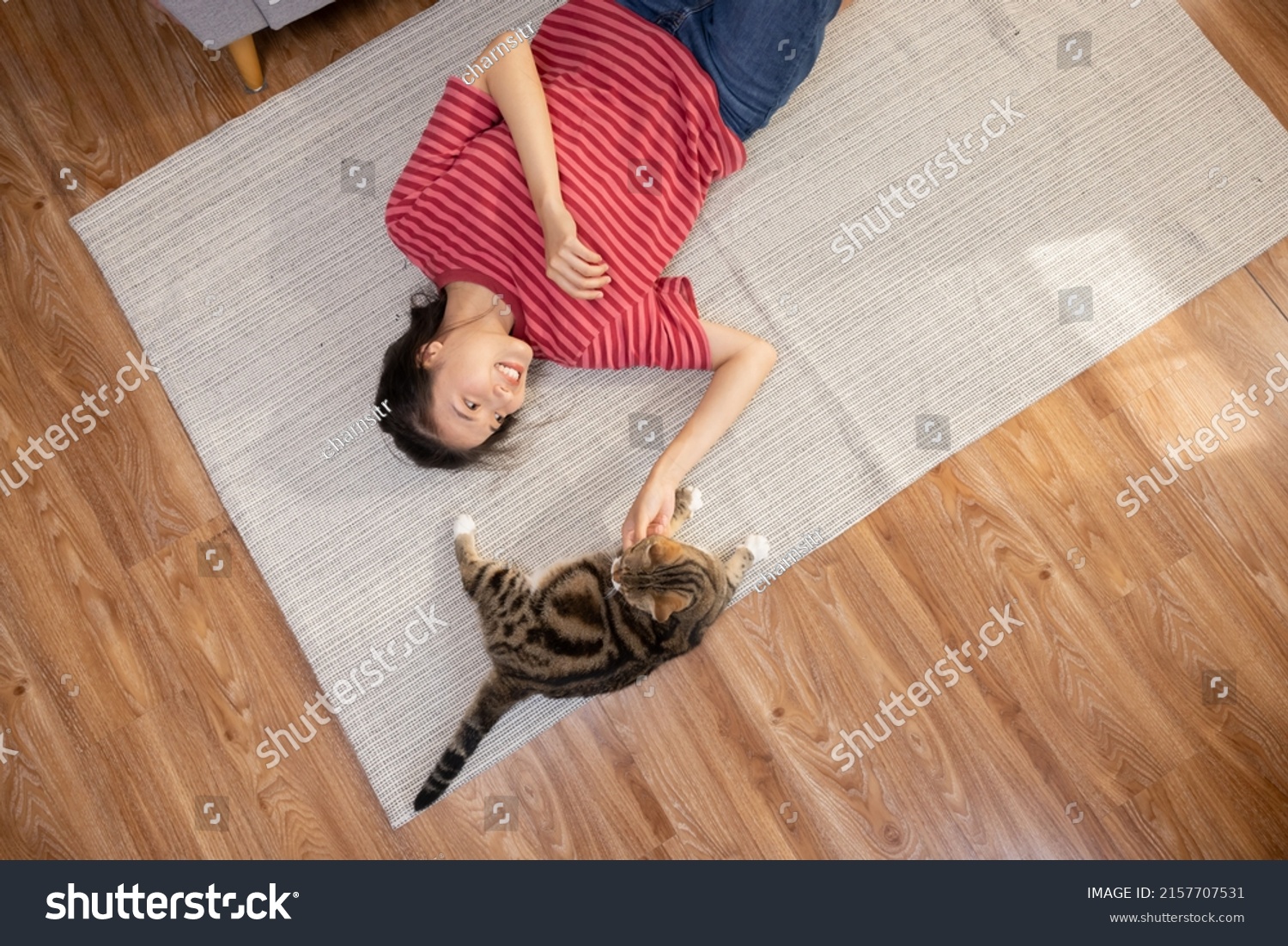 Top View of Asian Woman Lying on the Floor Playing with a Cat