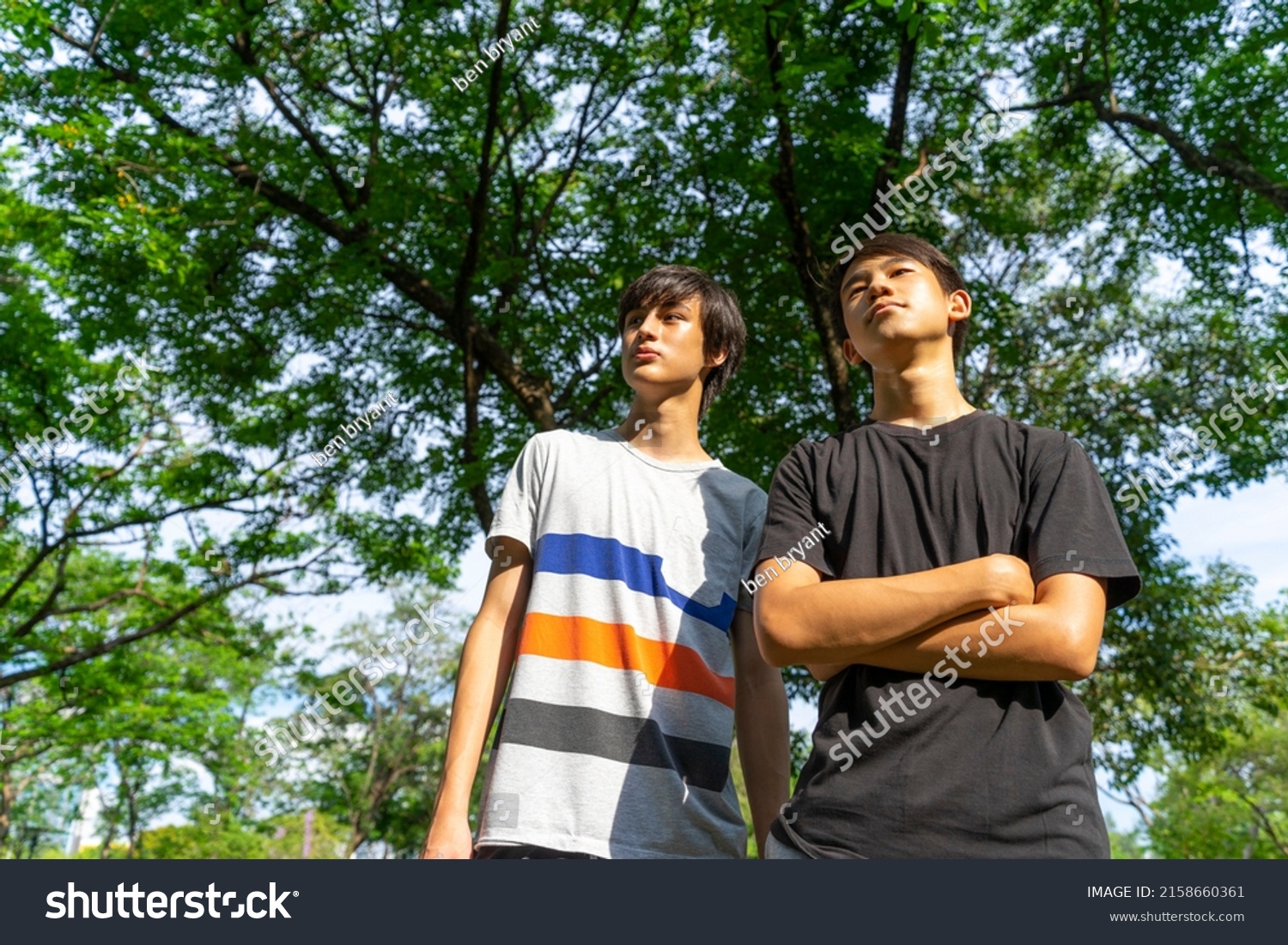 Two young happy smiling teen boy standing in green park background.