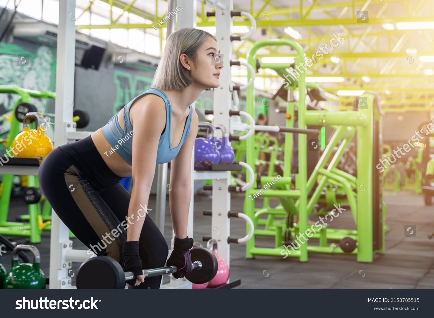 Young woman bodybuilder with barbell flexing muscles doing squats in gym. Concept of sports  gyms  fitness  bodybuilding. Preparing for the competition.