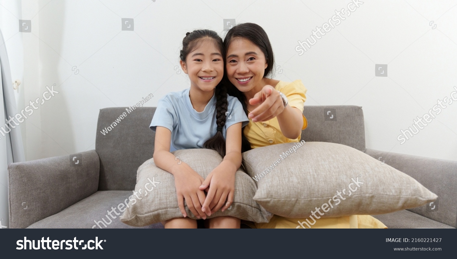 Excited young Asian mother and little girl watching television programs. Lifestyle and spends leisure at home.