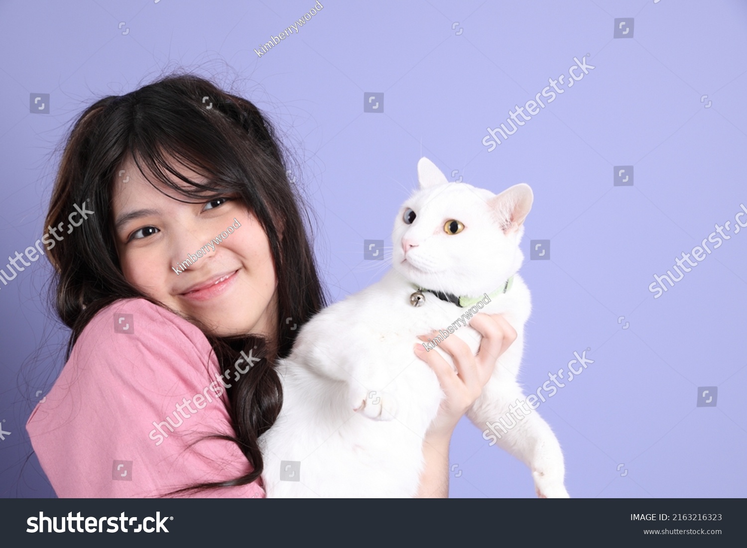 The cute young Asian girl with casual clothes standing on the purple background.