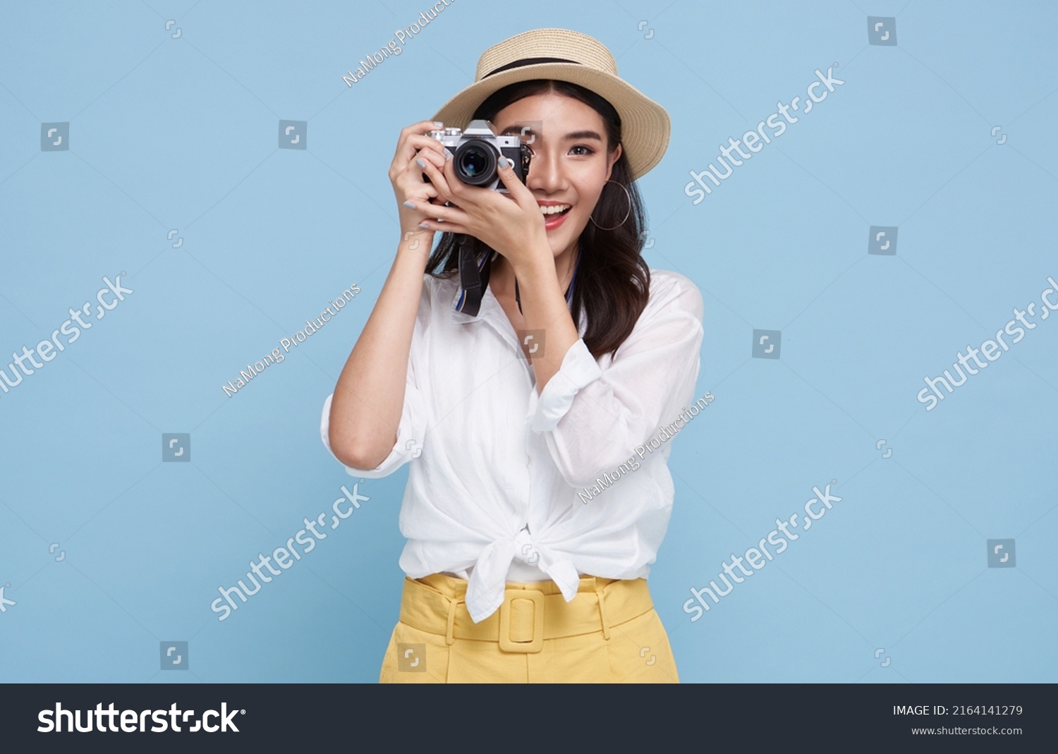 smiling Woman photographer is taking images photo with dslr camera isolated studio blue background.