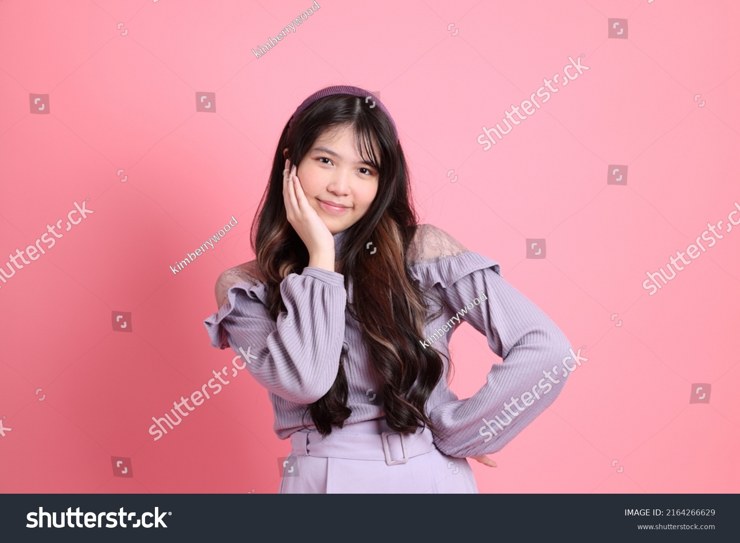 The cute young Asian woman with preppy dressed standing on the pink background.