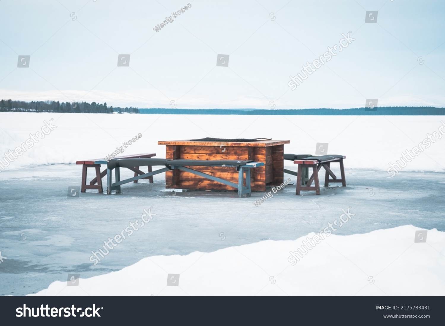Bonfire place with wooden benches on ice skating track called "medvinden" on lake storsjön near Östersund (Sweden Lapland).  Taking a cozy break on the melting ice. Copy space included.