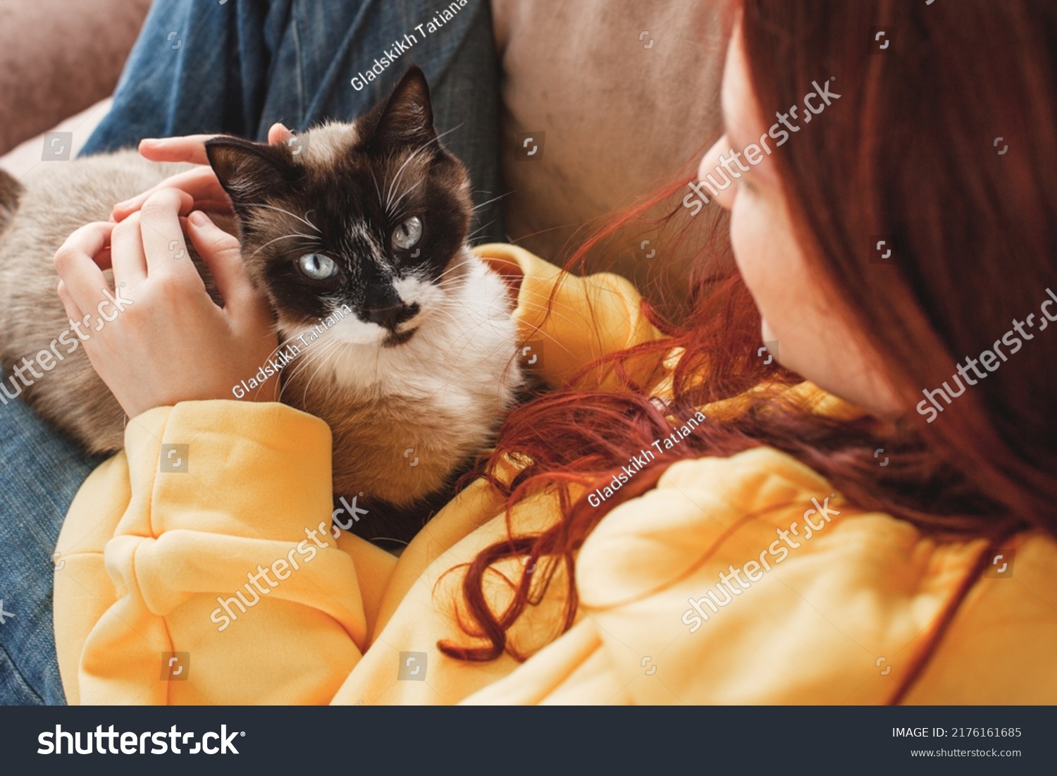 Happy young woman hugging and petting cat. Teen girl with cat on sofa at home