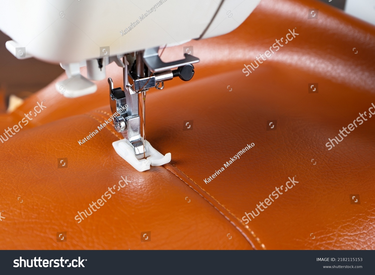 Modern sewing machine presser foot with a needle sews brown leather