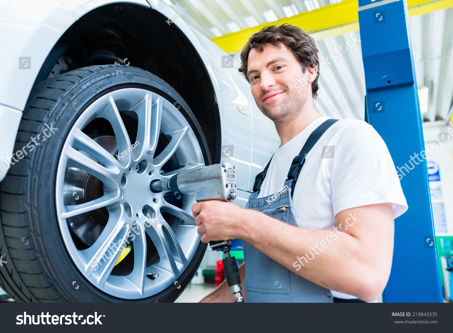 Male mechanic changing car tire or tyre in workshop