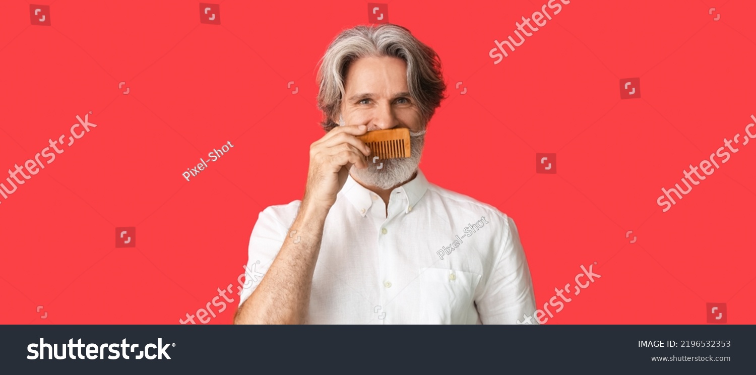 Stylish senior man with hair comb on red background with space for text