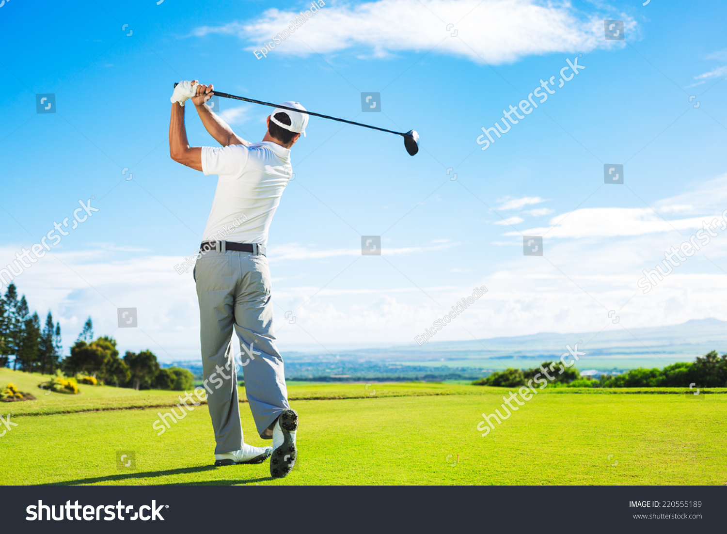 Man Playing Golf on Beautiful Sunny Green Golf Course. Hitting Golf Ball down the Fairway from the Tee with Driver. 