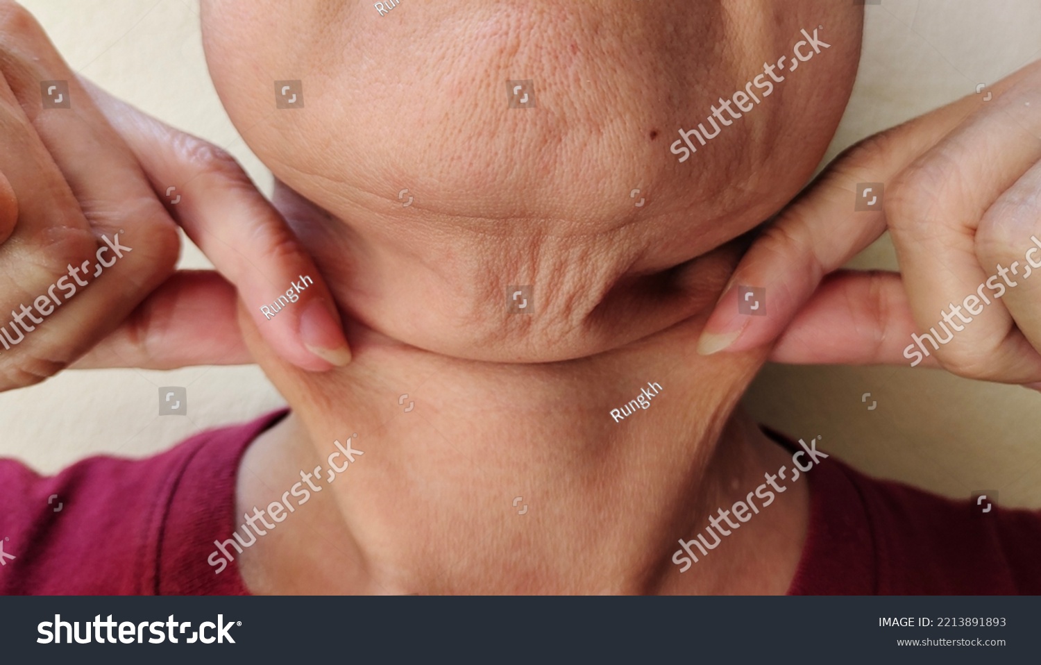 portrait the fingers squeezing the flabbiness adipose sagging skin under the neck wrinkles and flabby skin problem cellulite and rough skin under the chin of Middle-aged woman concept health care.