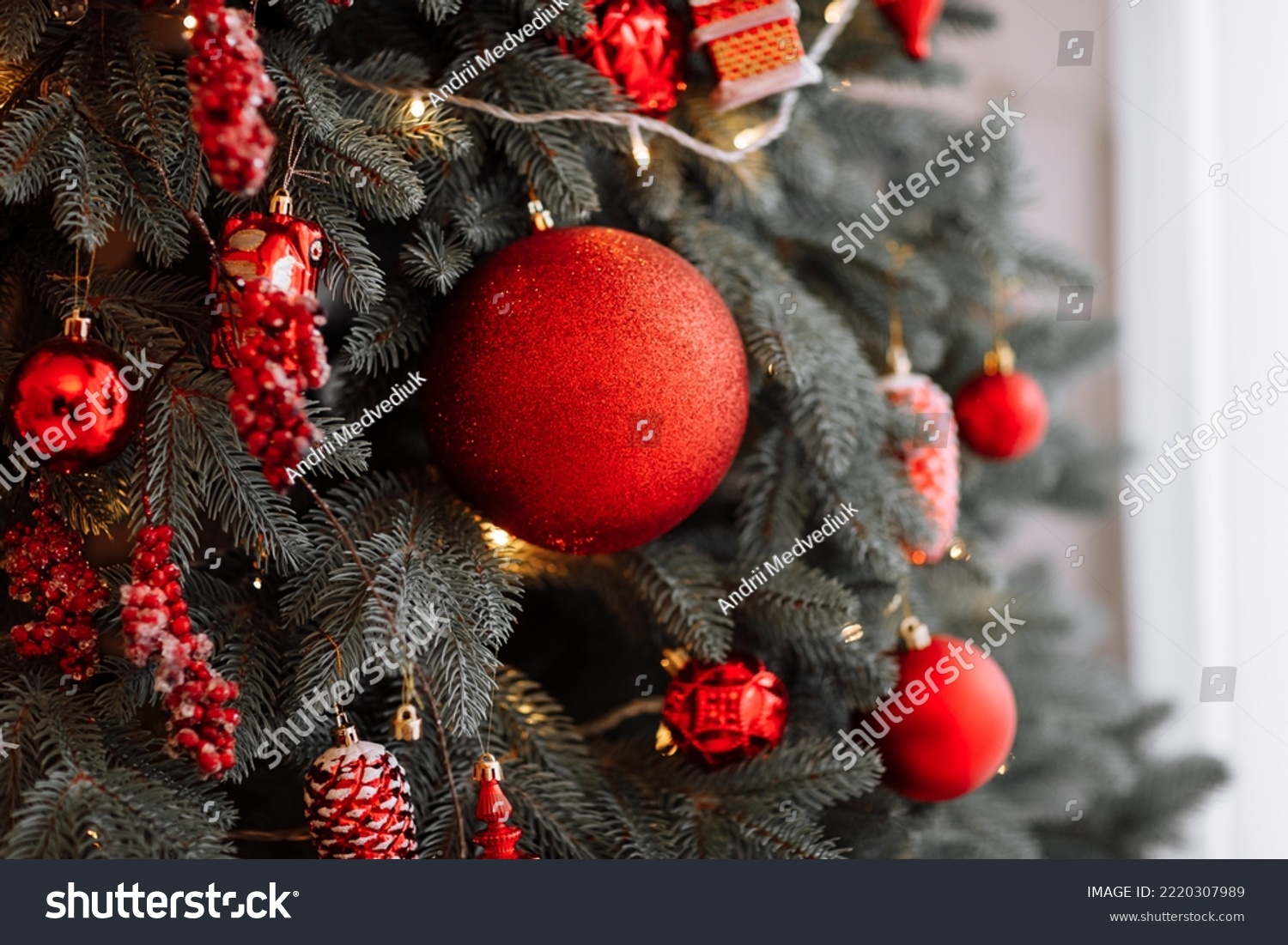 stylish christmas decorations on the tree beautiful toys balls cones and lights in red colours. Christmas cozy atmosphere in living room new year. Festive interior design